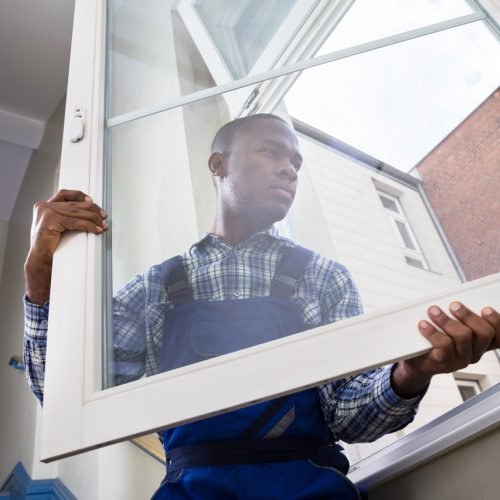 Repairman In Overalls Installing Window